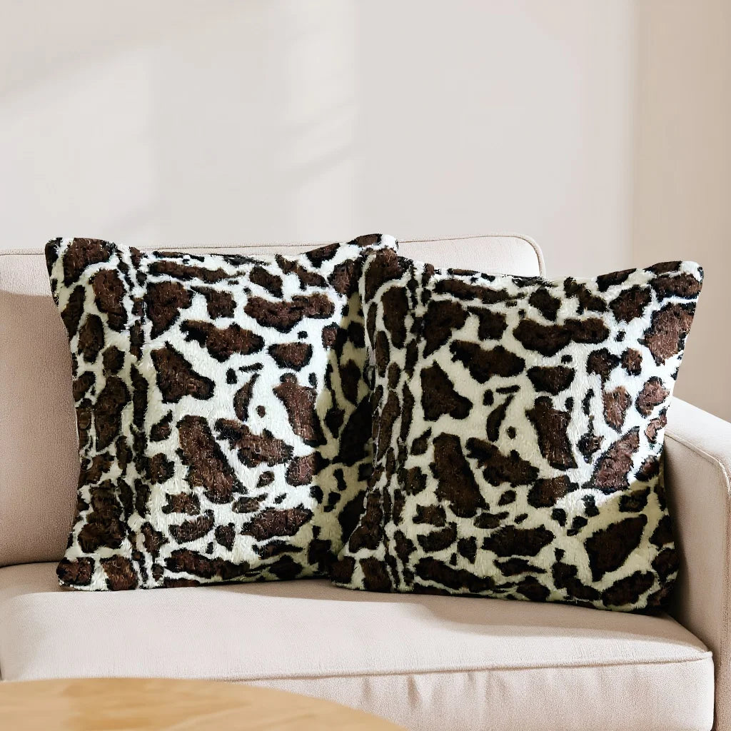 A set of two leopard print throw pillow covers resting on a light-colored sofa.