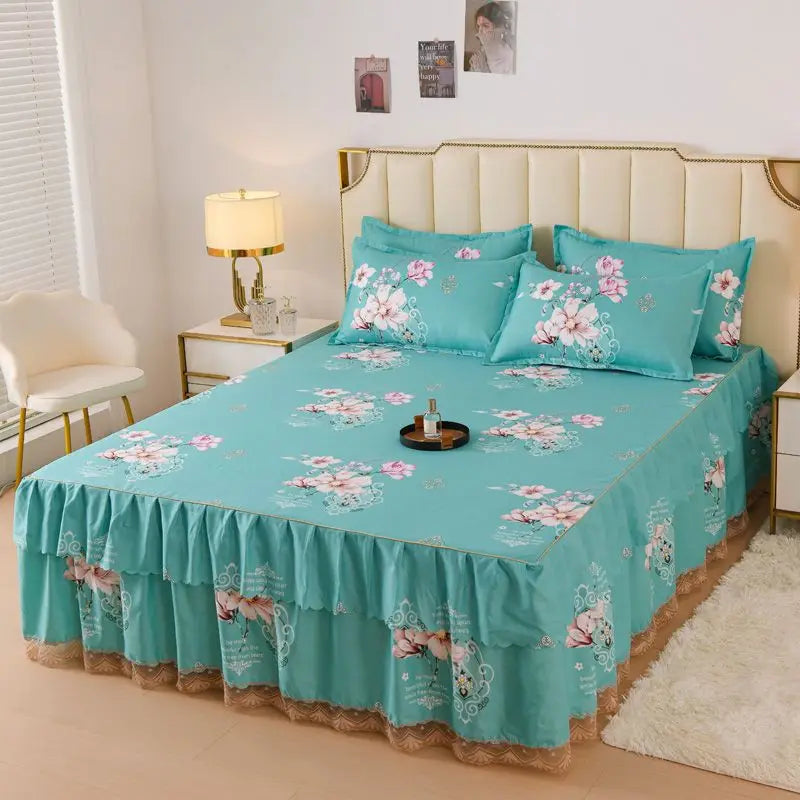 A teal floral bed skirt with pink and white flowers covers a bed, set against a light wall.