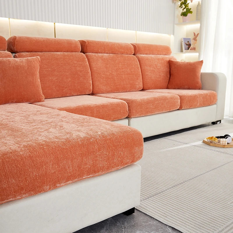An orange stretchable chenille sofa cushion cover on a white sofa with light wood accents.