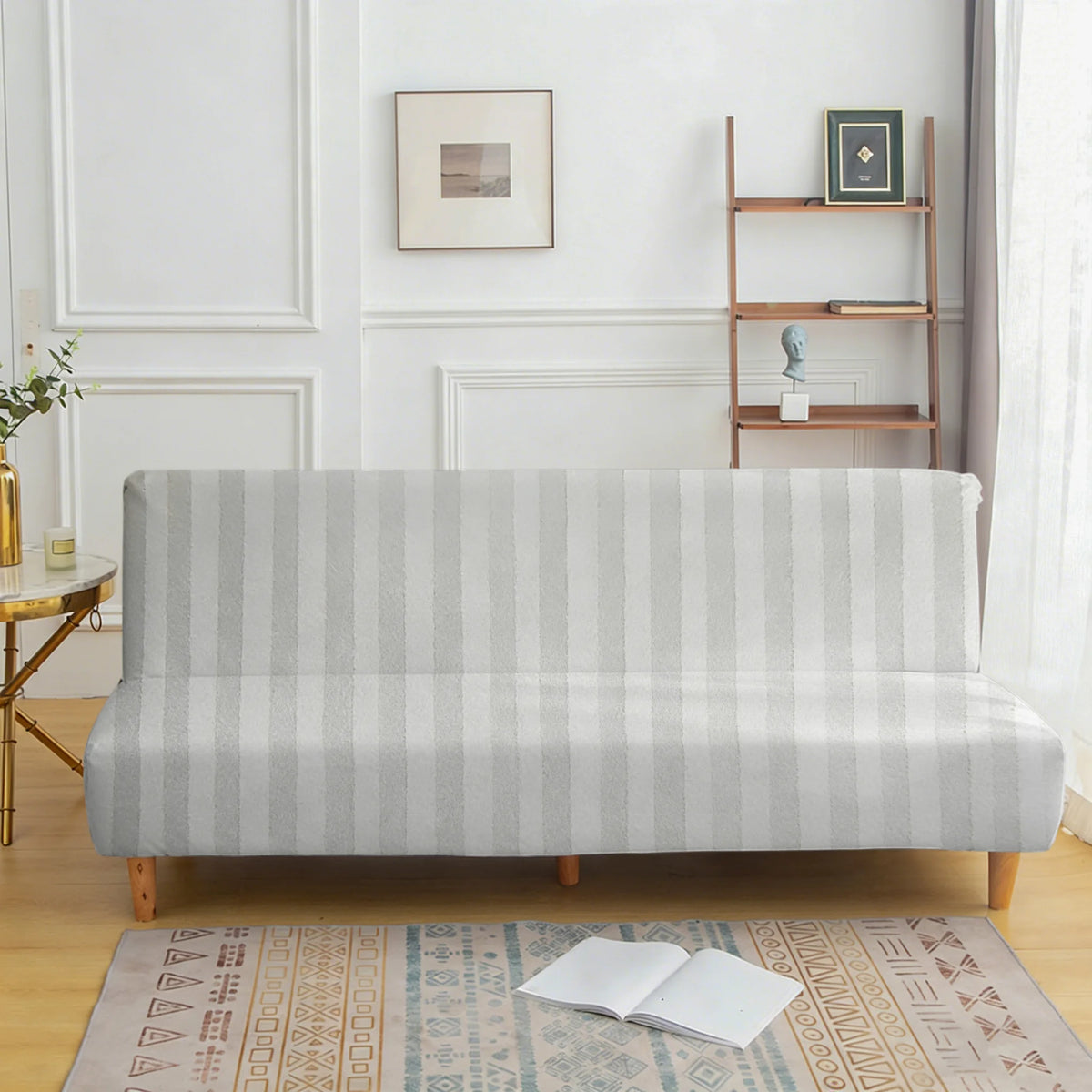 A light gray striped sofa cover displayed on a wooden bench in a bright room.