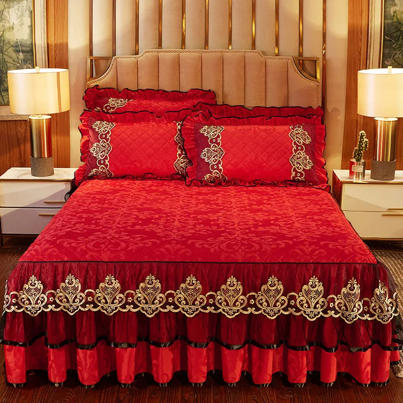 A vibrant red bed skirt set with matching pillowcases and a decorative embroidered border.