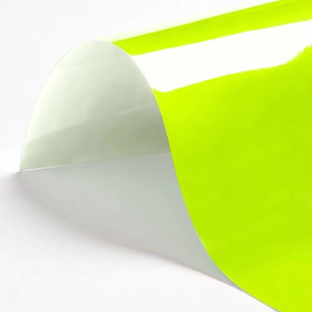 A sheet of bright lime green heat transfer vinyl being peeled off a white backing.