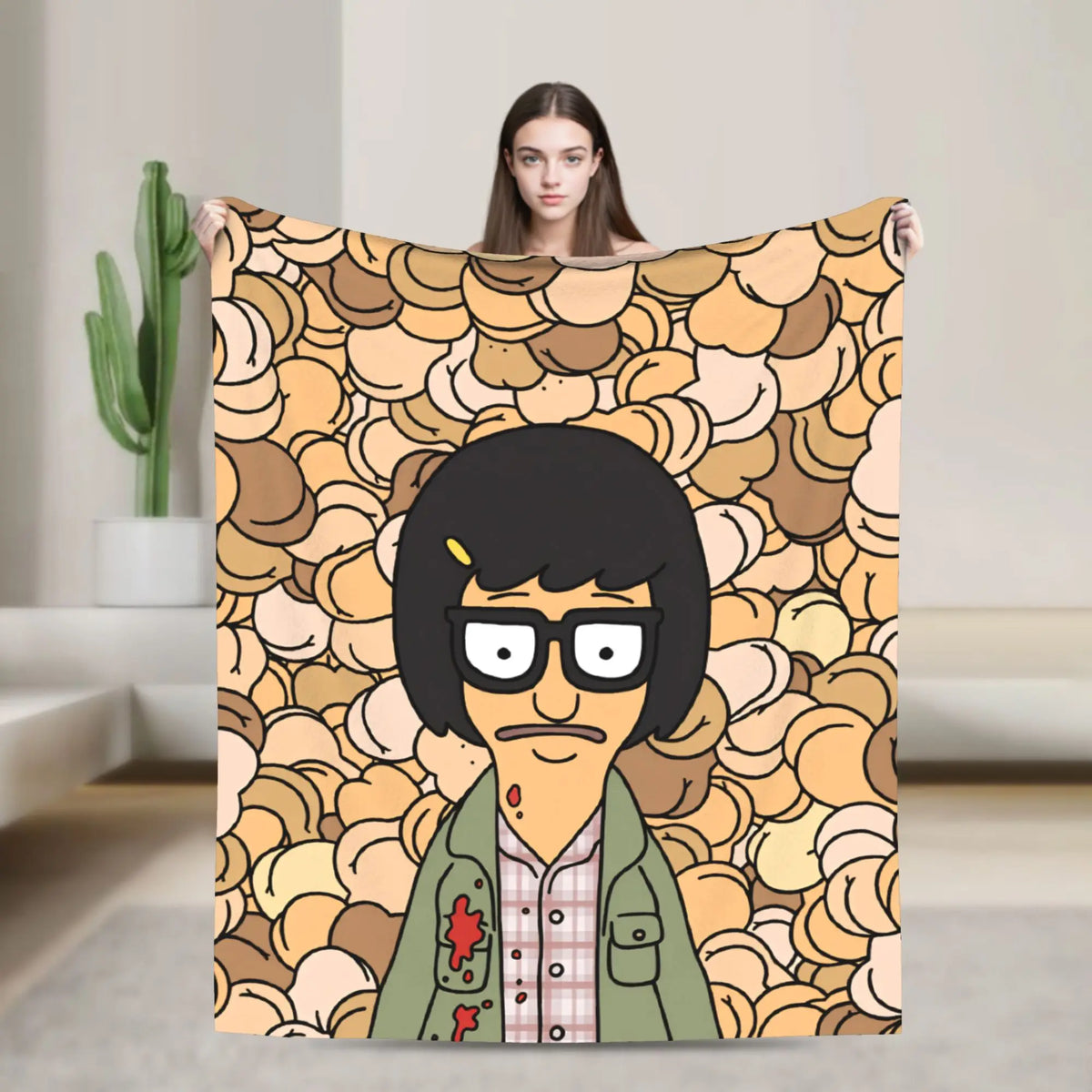 A person holds up a throw blanket featuring an anime-style character with black hair and glasses against a patterned backgrou