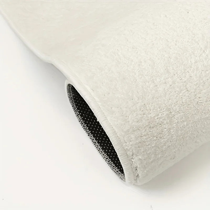 A close-up view of a thick, white, anti-slip decorative floor mat with a black trim.
