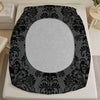 A black and gray floral skull pattern bed sheet set displayed on a white bed frame.