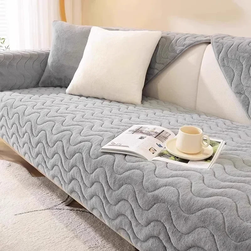 A gray plush anti-slip sofa seat cushion cover with white pillows and a cup of tea resting on it.