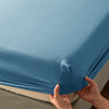 A hand is holding a light blue soft touch microfiber fitted sheet with deep pockets.