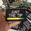 A black iron-on patch featuring the text JUST THE TIP and a yellow pencil design.