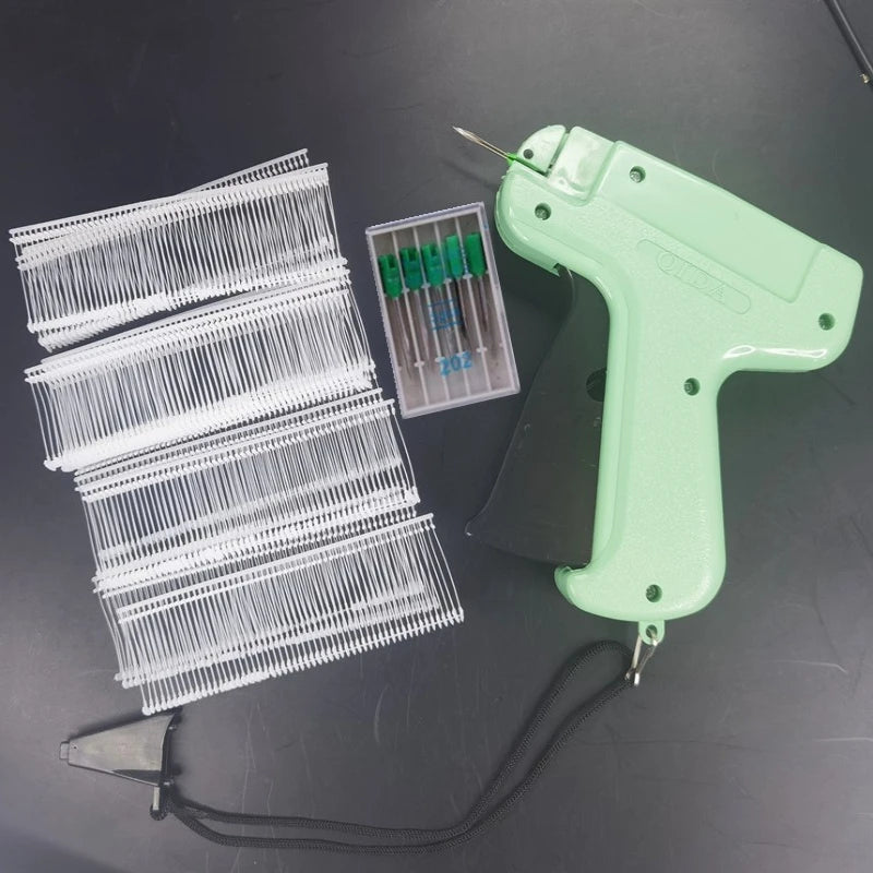 A light green precision sewing tag gun kit with multiple needles and a plastic holder is displayed on a dark surface.