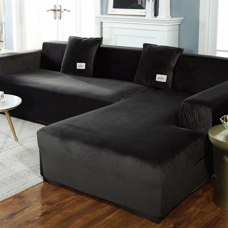 A dark gray velvet sofa cover for an L-shaped sectional with throw pillows in a living room setting.
