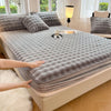 A fitted sheet set with a gray quilted cover and faux rabbit fur trim is laid out on a bed.