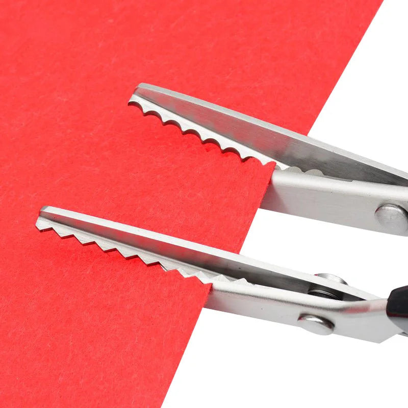 A pair of professional stainless steel pinking shears resting on a red piece of paper.