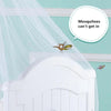 A mosquito net draped over a white crib railing with a small bee flying near it.