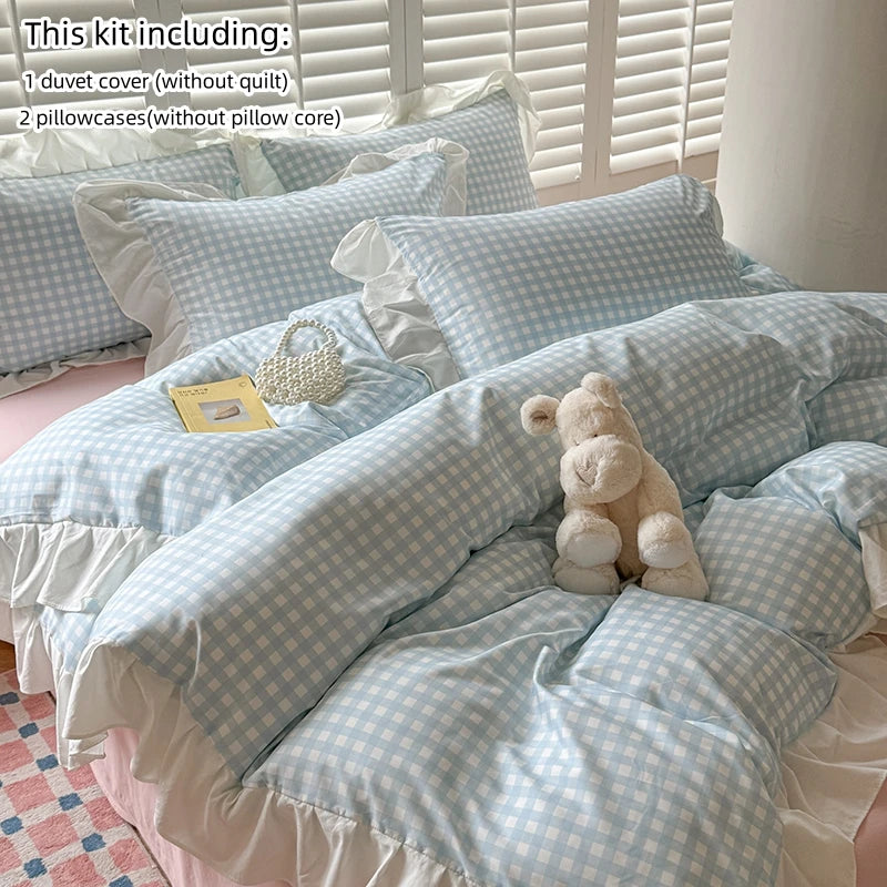 A set of light blue and white gingham bedding including a duvet cover, pillowcases, and a teddy bear.