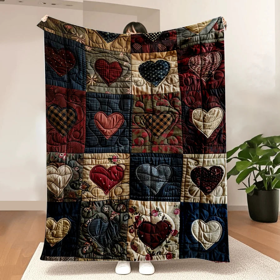 A patchwork flannel throw blanket featuring various heart prints in red, black, and gold tones.