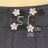 Gold and white floral adjustable buckles used as waist tighteners on gray fabric.