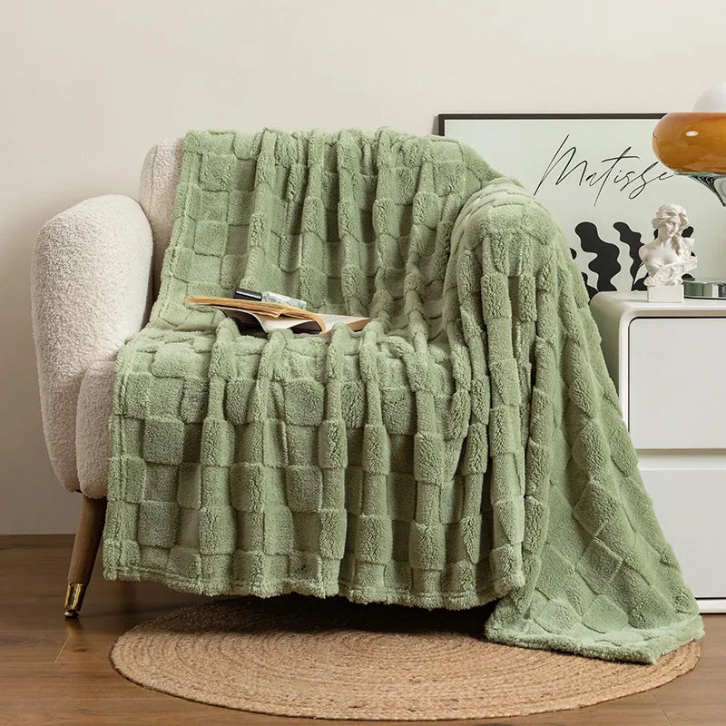 A light green checkered fleece throw blanket draped over a chair and resting on a woven rug.