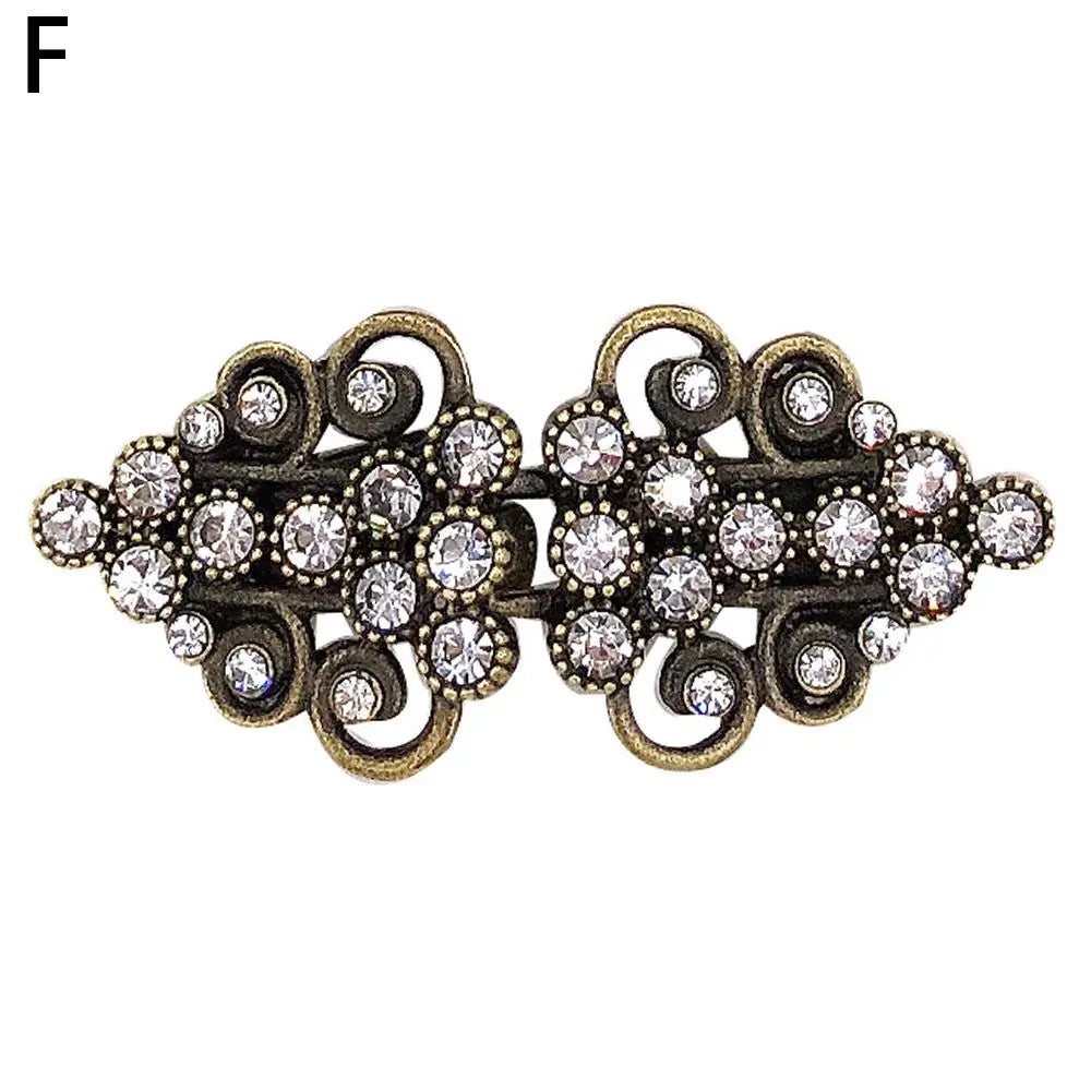 Vintage gold-toned swirl clip brooch featuring clear rhinestones and intricate metalwork