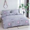 A gray bedding set featuring a pink heart print duvet cover and pillowcases on a bed.