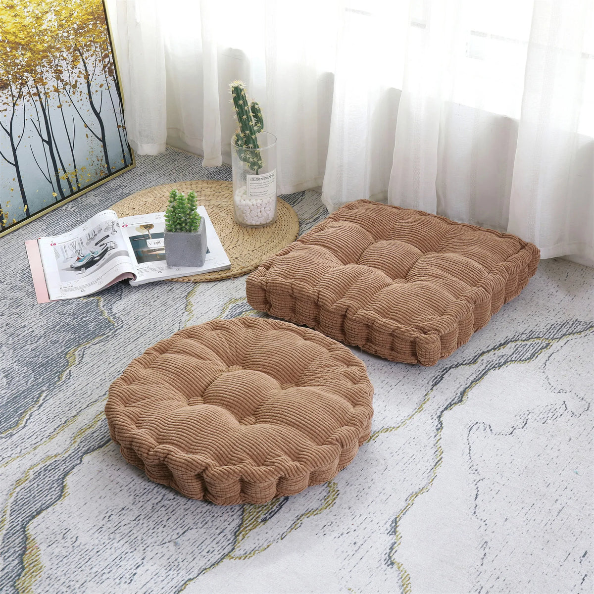 A brown tufted corduroy floor seat cushion resting on a light gray patterned rug near a window.