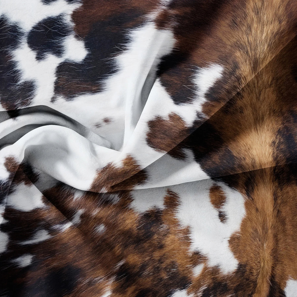 A close-up of a brown and black cow print fabric draped in soft folds.