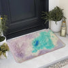 A thick silk wool area rug featuring a blend of purple and turquoise colors placed in front of a dark door.