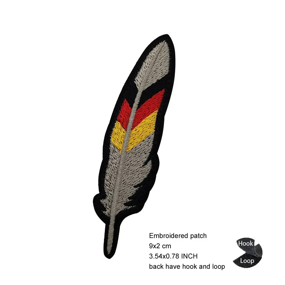Embroidered patch featuring a black feather with red, yellow, and gray stripes.