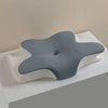 A gray ergonomic memory foam cervical pillow resting on a white textured surface.