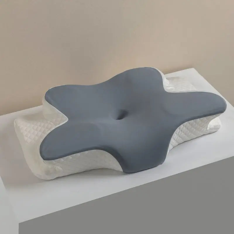 A gray ergonomic memory foam cervical pillow resting on a white textured surface.