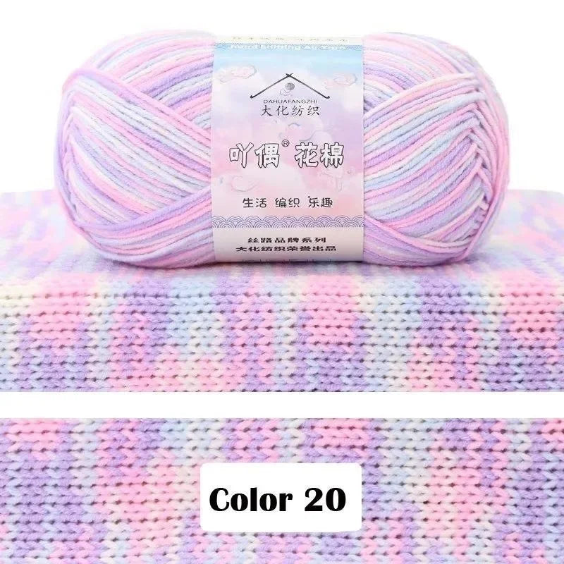 A ball of pink yarn with a gradient color pattern is displayed on a knitted fabric background.