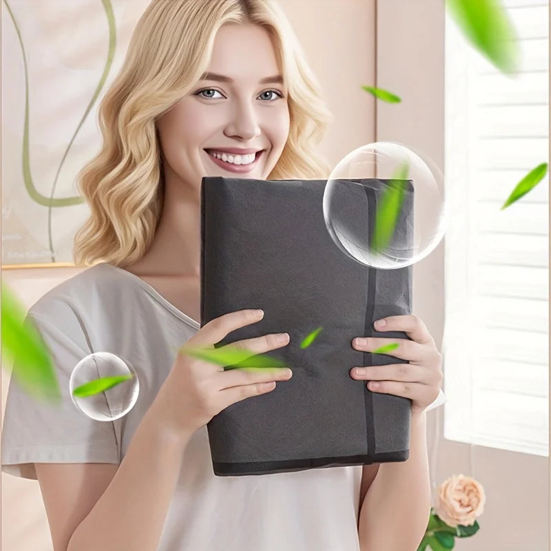 A smiling woman holds a large gray fabric storage bag with a zipper and handles in a bright indoor setting.