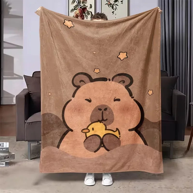 A plush flannel blanket featuring a cute cartoon bear face print on a tan background.