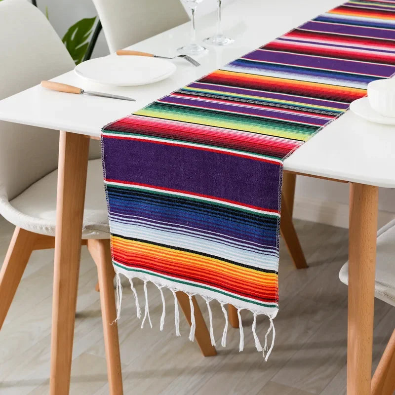 Colorful cotton Mexican sarape table runner with vibrant stripes on a white dining table.