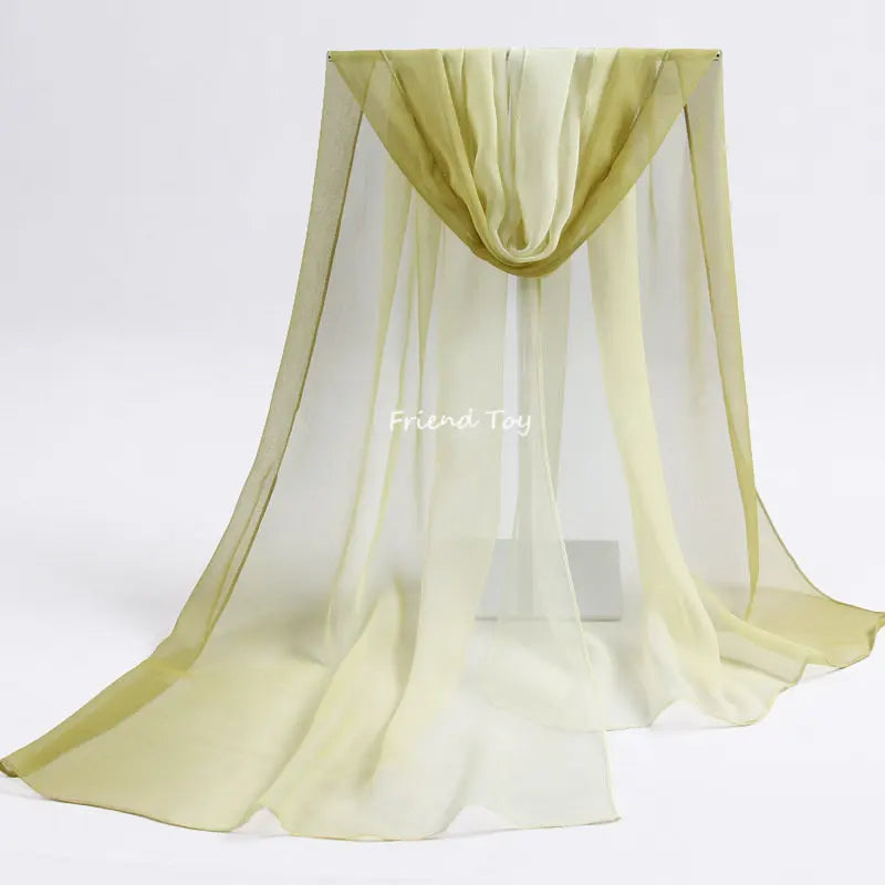 A sheer, light olive green fabric scarf draped in a flowing, pleated style for sensory play.