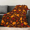 A dark orange and brown autumn leaf patterned fleece throw blanket draped over a gray sofa.