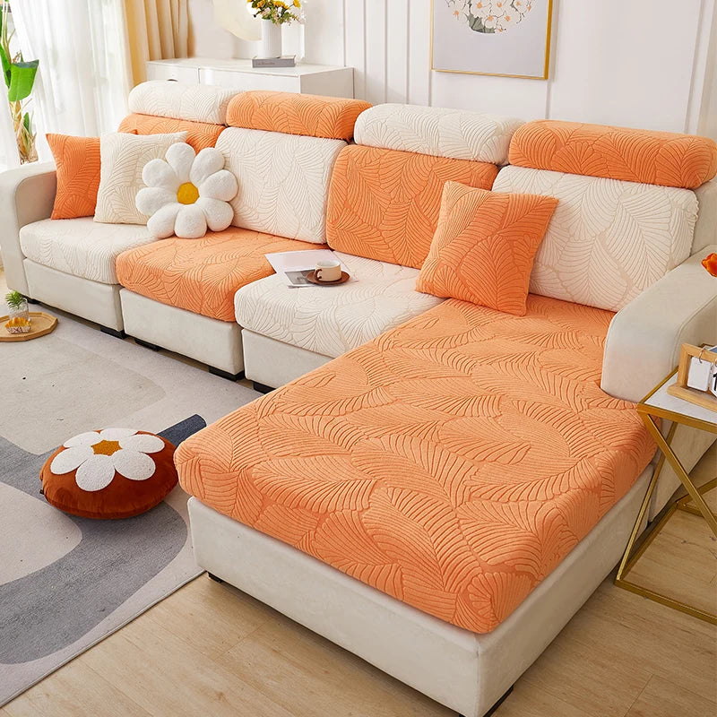 An orange leaf jacquard stretch sofa cover with anti-slip backing displayed on a white sectional sofa.