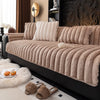 A beige thickened plush sofa seat cushion resting on a black sofa, with fluffy accents nearby.