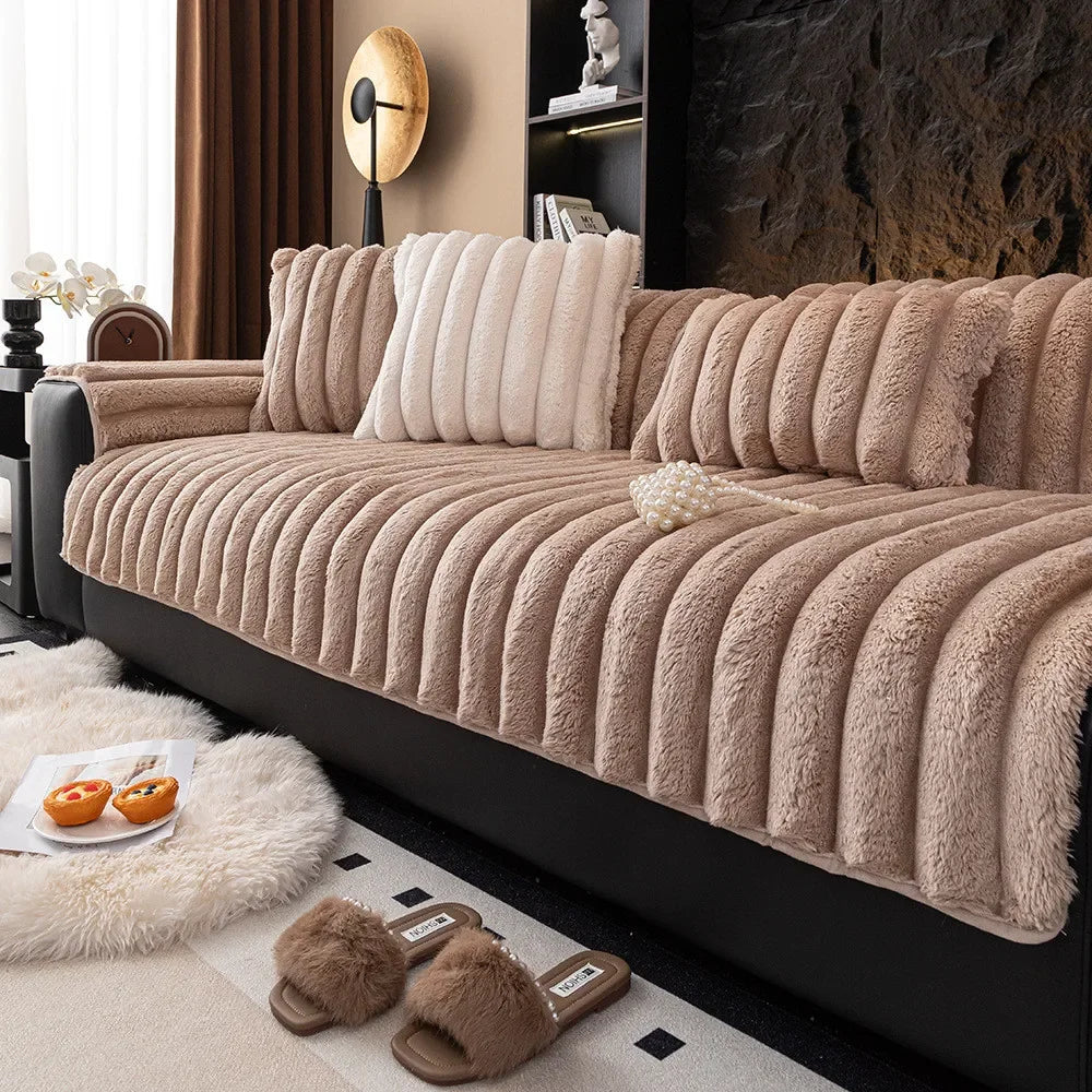 A beige thickened plush sofa seat cushion resting on a black sofa, with fluffy accents nearby.