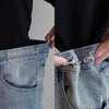 Close-up of a hand adjusting an adjustable waist tightening buckle on the pocket of denim jeans.