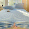 A light blue and white checkered flannel fitted sheet is laid out on a bed with matching pillows.