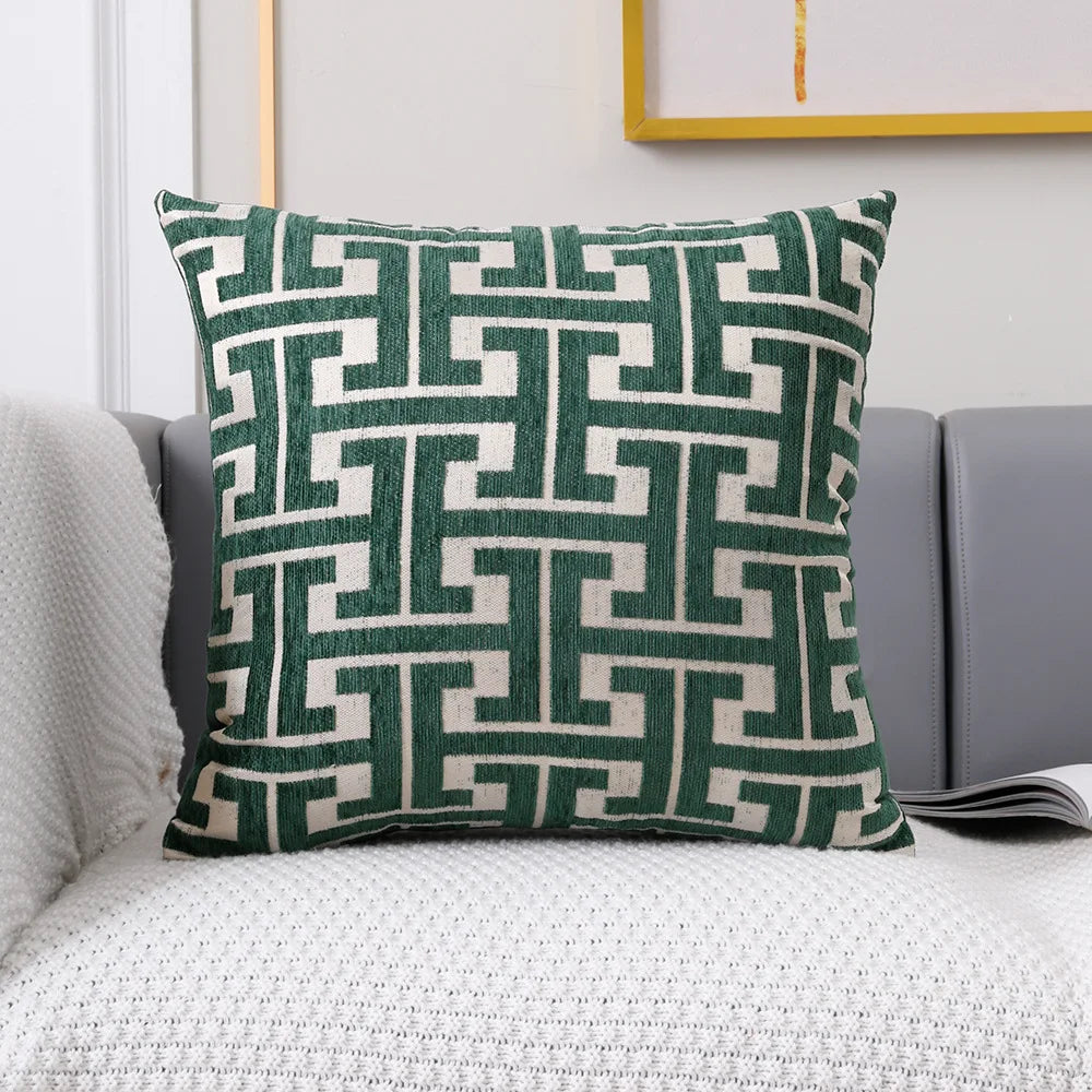 A square lumbar pillow cover featuring a geometric pattern in dark green and off-white tones.