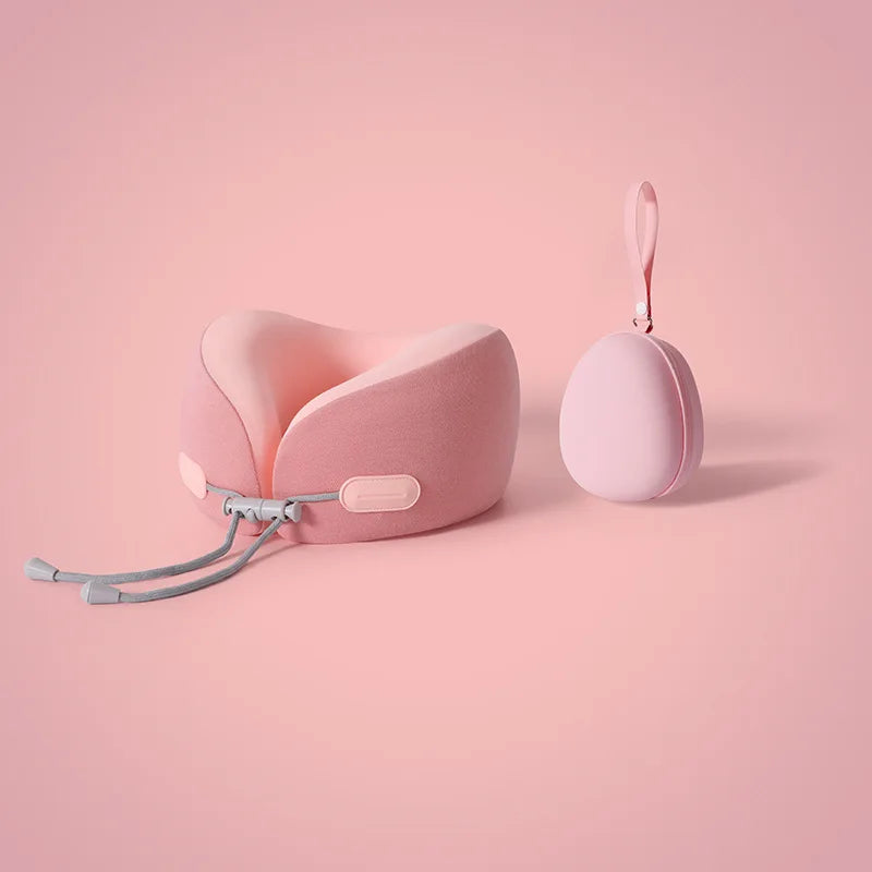 A pink U-shaped memory foam travel neck pillow with a cooling cover is shown against a light pink background.