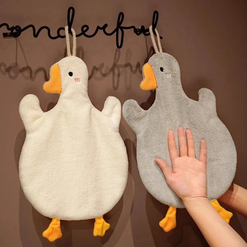 A fluffy white cartoon goose hanging decoration against a brown wall.