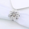 Silver metal napkin rings with a floral design displayed on a white linen cloth.