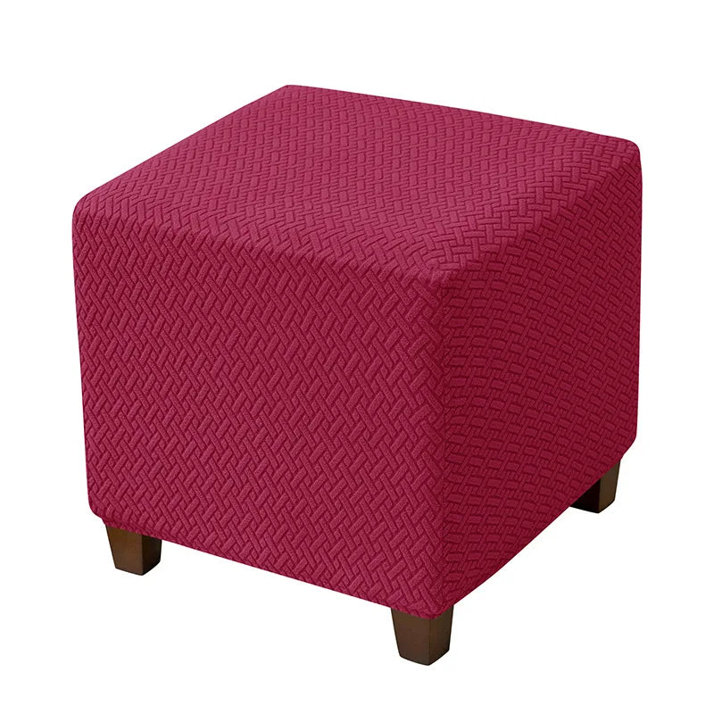 A square ottoman slipcover in a deep magenta color with a textured diamond pattern.