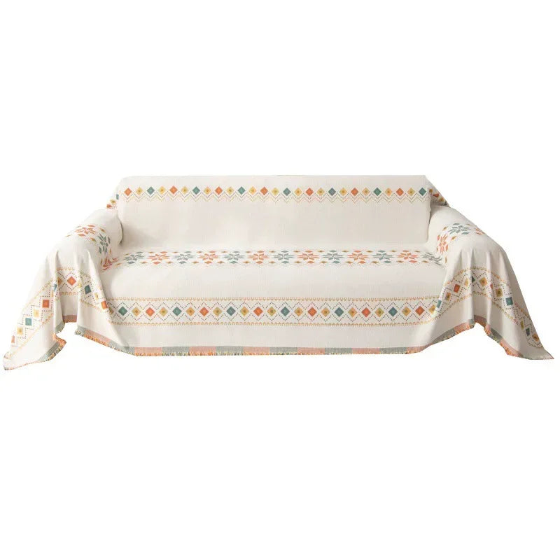 A beige accent sofa cover featuring a geometric patterned design with orange and teal accents.