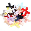 A collection of various satin ribbon bows in shades of black, pink, yellow, blue, and red.