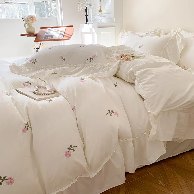 White duvet cover set with pink embroidered roses on a bed
