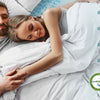 A couple relaxing on a bed with a white memory foam topper, demonstrating its support and ergonomic design.