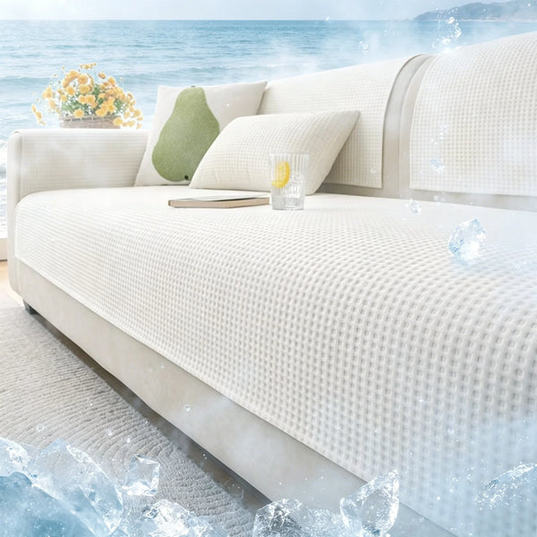 A white machine washable anti-slip sofa slipcover with light green pillows and ice cubes on a deck.